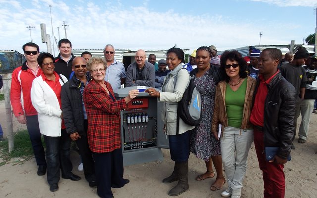 Burgemeester Nicolette Botha-Guthrie en Raadslid Theodorah Nquinata, omring deur raadslede, munisipale beamptes en die kontrakteurs tydens die seremonie met die aanskakeling van elektrisiteit vir 85 informele wonings in Masakhane